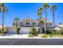 Stunning two-story home featuring a three-car garage, mature landscaping, and tall palm trees in a sunny neighborhood at 9905 Fox Springs Dr, Las Vegas, NV 89117