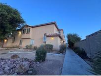 Inviting two-story townhouse with desert landscaping, warm lighting, and a private walkway at 558 Roxella Ln # D, Las Vegas, NV 89110