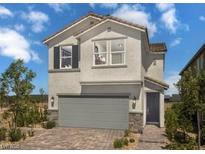 Charming two-story home with a gray garage door, stucco, stone accents, and a paver driveway at 7388 Daly Grove St, Las Vegas, NV 89113