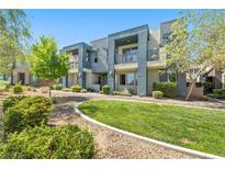 Modern townhome showcasing a manicured lawn, stucco facade, recessed balconies, and mature landscaping at 11239 Cactus Tower Ave # 102, Las Vegas, NV 89135