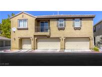 Three-unit tan townhome featuring individual garages and a small balcony on the second level at 3905 Sweet Pine St # 102, Las Vegas, NV 89108
