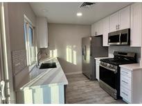 Modern kitchen features white cabinets, stainless steel appliances, and light countertops at 7144 Forest Vista St, Las Vegas, NV 89147