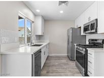 Modern kitchen features white cabinets, stainless steel appliances, and light countertops and tiled backsplash at 7144 Forest Vista St, Las Vegas, NV 89147