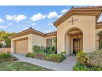Inviting single-story home featuring a Mediterranean-style facade, arched entrance and manicured landscaping at 37 Stonemark Dr, Henderson, NV 89052