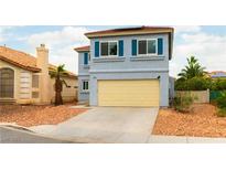 Two-story home with a blue exterior, red roof, tan garage door, and a desert-landscaped front yard at 8484 Montana Stream Ave, Las Vegas, NV 89113
