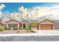 Inviting single-story home with a three-car garage and desert landscaping under a blue sky at 1641 Rockcrest Hills Ave, Henderson, NV 89052
