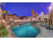 Backyard pool featuring rock waterfall, decorative lighting, and mature landscaping at 1717 Jake Andrew Ave, North Las Vegas, NV 89086