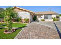 Charming single-story home with manicured lawn, brick-paved driveway and charming curb appeal on a sunny day at 2112 Los Altos St, Las Vegas, NV 89102