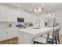 Modern kitchen featuring white cabinets, stainless steel appliances, quartz counters and stylish gold pendant lighting at 2742 Zazzera Ct, Henderson, NV 89044