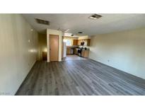 Open-concept living room showcases new flooring, leading to kitchen with ample cabinet space and natural light at 3412 Mercury St # I, North Las Vegas, NV 89030