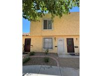 Townhouse exterior featuring tan stucco, security doors, and landscaped front yard with decorative rock at 453 Las Casitas Way, Las Vegas, NV 89121