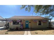 Charming single-story home with a bright turquoise door and festive patriotic decorations on a sunny day at 517 5Th St, Boulder City, NV 89005