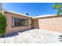 Low angle view of a tan single-story home featuring a secure window, and a tan front door at 805 E Carey Ave, North Las Vegas, NV 89030