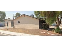 Side view of a modest stucco home with a low-pitched roof, desert landscaping, and mature trees at 3114 Scarlet Oak Ave, Las Vegas, NV 89104