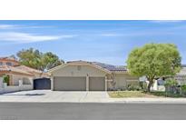 Charming single-story home with a well-manicured front yard, three-car garage and solar panels on the roof at 814 Singing Drum Dr, Henderson, NV 89002