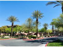 Community street view with palm trees, lush landscaping, and well-maintained pathways under a bright blue sky at 908 Duckhorn Ct # 102, Las Vegas, NV 89144