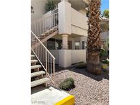 Exterior view of condo with metal stair rails and xeriscaping in a residential neighborhood at 925 Falconhead Ln # 102, Las Vegas, NV 89128