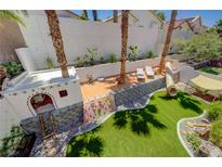 An elevated view of a backyard with a climbing wall, playground, turf, lounging area and privacy wall at 189 Andada Dr, Henderson, NV 89012