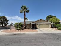 Charming single-story home features a two-car garage, complemented by lush landscaping and a palm tree at 7104 Carrondale Way, Las Vegas, NV 89128