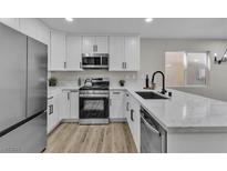 Bright kitchen features white cabinetry, stainless steel appliances, and solid surface countertops at 10373 Midnight Iris St, Las Vegas, NV 89183