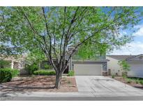 Charming two-story home with a two-car garage, landscaped front yard and mature trees at 1553 Ivygate Ave, Las Vegas, NV 89183