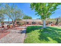 Charming home showcasing xeriscaping, mature trees, and lush green grass, perfect for enjoying outdoor desert living at 1705 Westwind Rd, Las Vegas, NV 89146