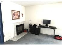 Cozy living room with decorative fireplace, light gray carpet, and a workspace setup at 3150 Soft Breezes Dr # 1192, Las Vegas, NV 89128