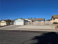 Single story home with desert landscaping, white garage door and blue roof at 725 Brick Dr, Henderson, NV 89002