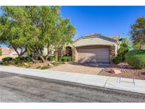 Charming single-story home with stone accents, mature trees, and a well-manicured front yard under a bright blue sky at 1897 Holdenville St, Henderson, NV 89052
