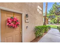 Inviting home entrance with a pink floral wreath, light fixture, and lush green bushes lining the walkway at 2050 W Warm Springs Rd # 1923, Henderson, NV 89014