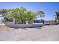 Charming home featuring a secure gated perimeter, mature trees, and ample yard space at 4490 W Warm Springs Rd, Las Vegas, NV 89118
