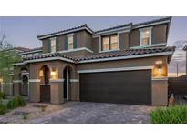 Charming two-story home with a brick driveway, arched entryway, and dark brown garage door at 6909 Toll Mountain St, North Las Vegas, NV 89086