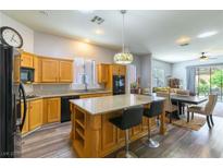 Well-lit kitchen with a large island, modern appliances, and wood-look flooring flowing into the dining area at 1004 Viale Placenza Pl, Henderson, NV 89011
