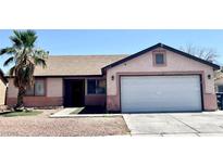 Charming single-story home featuring a well-kept yard with a palm tree and a two-car garage at 2405 Prime Advantage Ave, North Las Vegas, NV 89032