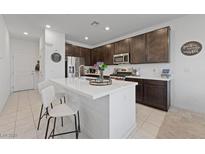 Modern kitchen featuring an island with seating, stainless steel appliances, and dark wood cabinetry at 2732 Roman Palm Rd, North Las Vegas, NV 89086