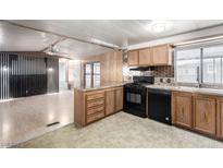 Well-lit kitchen featuring wood cabinets, granite counters, a black appliance package, and designer backsplash at 3471 Cape Cod Dr, Las Vegas, NV 89122