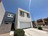 Modern two-story home features a two-car garage and neutral stucco, near a paved driveway and green shrubbery at 6450 Cinnamon Hazlenut St, North Las Vegas, NV 89084