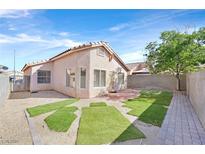 An outdoor space with artificial grass patches, a brick patio, rock landscaping, and block wall fencing at 7920 Turtle Island Ct, Las Vegas, NV 89129