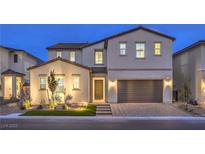 Two-story home boasting stucco exterior, a two-car garage, and a manicured front yard illuminated by landscape lighting at 8984 Rolling Pietra St, Las Vegas, NV 89166