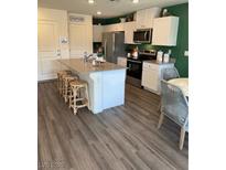 Modern kitchen with white cabinetry, stainless steel appliances, and a center island with bar seating at 1900 Arietta Vista St, Henderson, NV 89044