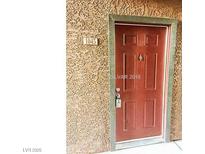 A classic six-panel front door, painted a rich maroon and secured with a modern keypad lock, welcomes visitors to home number 1045 at 2451 N Rainbow Blvd # 1045, Las Vegas, NV 89108