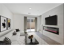 Bright living room featuring a white sofa, modern fireplace, and sliding glass door to the backyard at 2747 Tahiti Grape Way # 2, Las Vegas, NV 89183