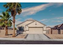 Charming single-story home featuring a two-car garage, desert landscaping, and mature palm trees at 5028 Crying Heart St, North Las Vegas, NV 89031