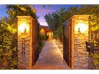 Grand gated entrance featuring stone pillars and lush landscaping, creating an inviting approach to the property at 5680 N Fort Apache Rd, Las Vegas, NV 89149