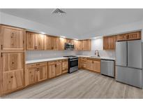 Modern kitchen with stainless steel appliances, wooden cabinets, white countertops, and light tile backsplash at 6741 Bonillo Dr, Las Vegas, NV 89103