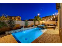 Backyard pool and spa with water features, brick pavers, landscape, and lounge area with string lights overhead at 7311 Spring Flower Ave, Las Vegas, NV 89117