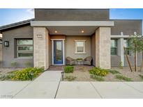 Charming front porch with blue door, stone columns, brick floor and a cozy seating area at 912 Allister Fields Ln, Las Vegas, NV 89138