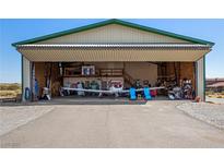 View of Airplane Hangar, concrete floor, with bi-fold door open, airplane inside, and storage shelves at 1100 Mitchell Pl, Pahrump, NV 89060