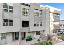 Contemporary townhome featuring a light gray facade, multi-pane windows, and well-kept brick paver courtyard at 659 Spotted Falcon St, Las Vegas, NV 89138