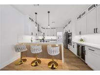 Bright kitchen with white cabinets, quartz countertops, wood floors, and stylish barstool seating at the island at 9900 Summer Ash Ct # 103, Las Vegas, NV 89134